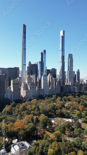 Low to high drone circle over Central Park showing skyline and bright fall colors
