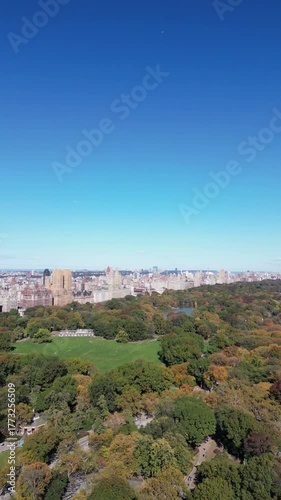 Reverse drone orbit showcasing Manhattan skyline and Central Park under blue skies