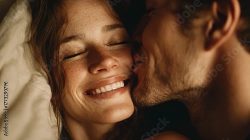 Intimate Moment of a Couple Smiling and Enjoying Each Other's Company in a Cozy Bedroom Setting on a Soft Bed with Natural Light