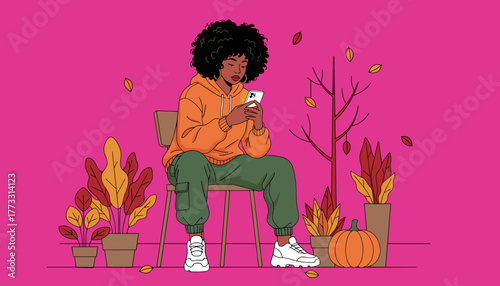 Girl in hoodie sitting using cell phone amidst fall decor Modern youth and technology