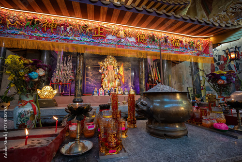 Golden chinese deity surrounded by smaller deities in a shrine