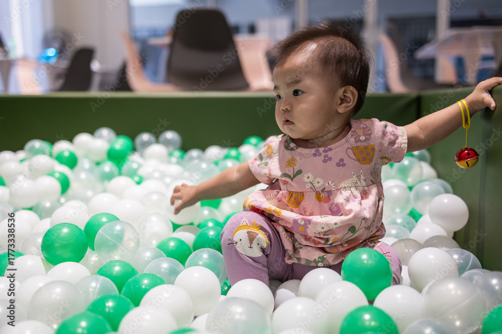 Fototapeta premium Adorable baby girl playing in a ball pit