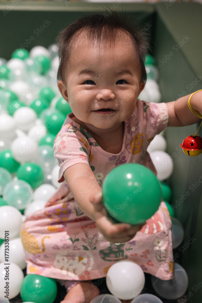 Obraz premium Adorable baby girl playing in a ball pit
