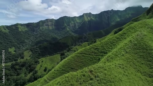 Lush Green Rolling Hills and Majestic Mountains Under a Cloudy Sky.