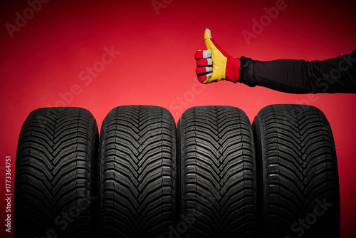 Car tires service and hand with thumb up of mechanic or driver  on red background, formula racing, speed drive and wheels concept
