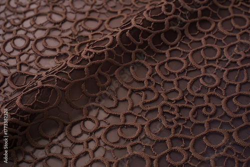 Closeup of intricate brown lace fabric with a delicate floral pattern