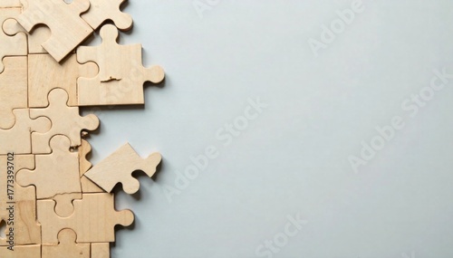 Empty space in a jigsaw puzzle, hinting at an incomplete idea or solution. An overhead shot of a partially assembled wooden jigsaw puzzle on a neutral, textured surface. A distinct, irregularly shaped
