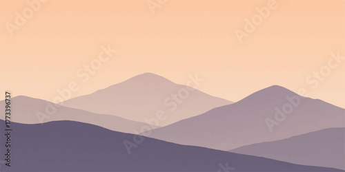 The mist-covered mountain range is a majestic blue silhouette against the morning sky at sunrise