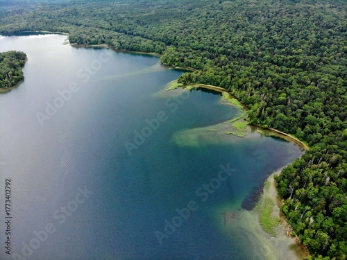 Obraz na plátně Diagonal drone view of forested shoreline, coves, and turquoise shallows at Lake