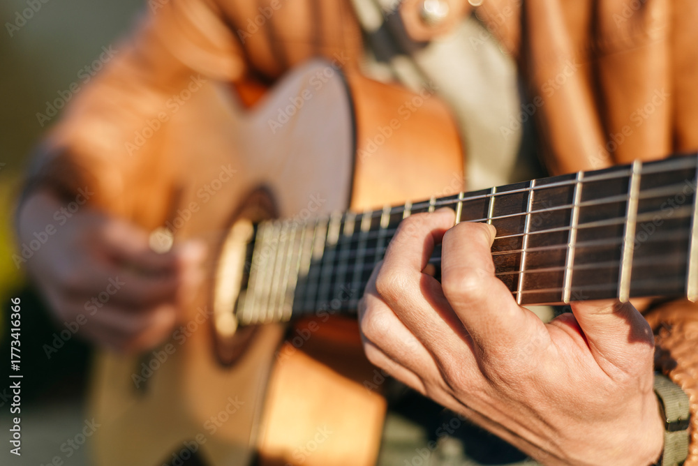Fototapeta premium Musician playing acoustic guitar outdoors, close-up on hands and fretboard