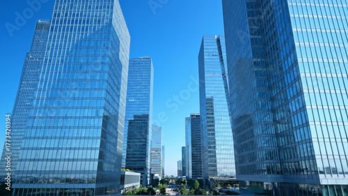Modern glass skyscrapers stand tall against a clear blue sky.