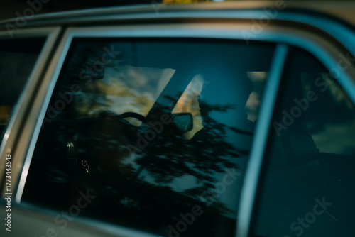 Cinematic reflection of man inside vintage car through window glass, moody retro composition combining shadows, light, and nostalgia for timeless storytelling.