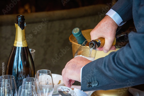 Man pouring champagne into a drinking glass in a restaurant.