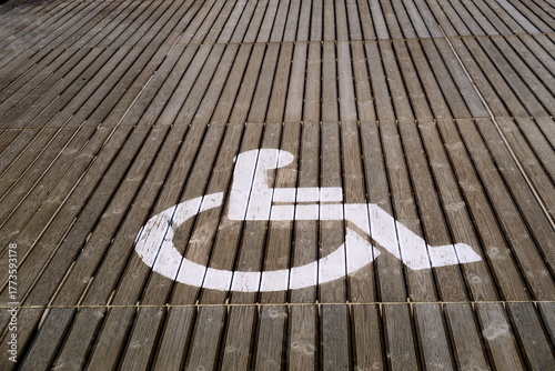 Panneau PMR (Personnes à Mobilité Réduite) sur un plancher en bois de terrasse extérieure.