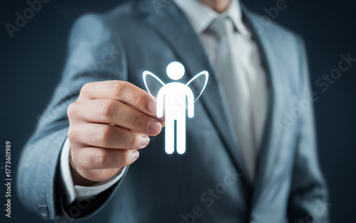 Professional business photo of a hand in a gray suit and blue striped tie reaching out to touch a glowing white digital human icon in a circular translucent frame against a dark blue blurred backgroun