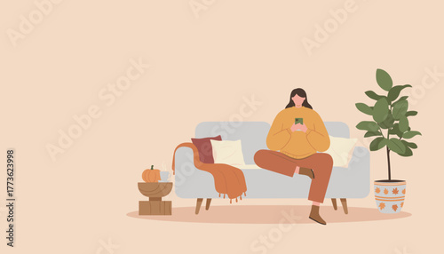 Cozy woman relaxing on sofa using smartphone at home during fall season