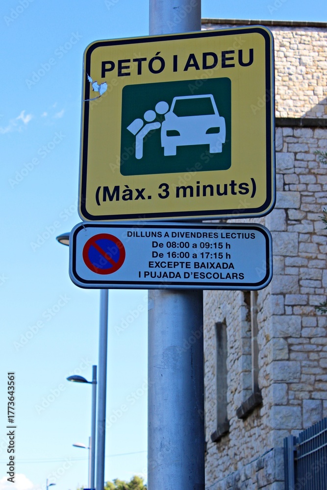 Fototapeta premium Funny Catalonia traffic sign 'Petó i Adeu' (Kiss and Go) indicating a short stop zone near a school, photographed on a sunny day in Spain.