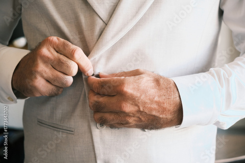 Groom fastening jacket button — candid preparation, landscape orientation