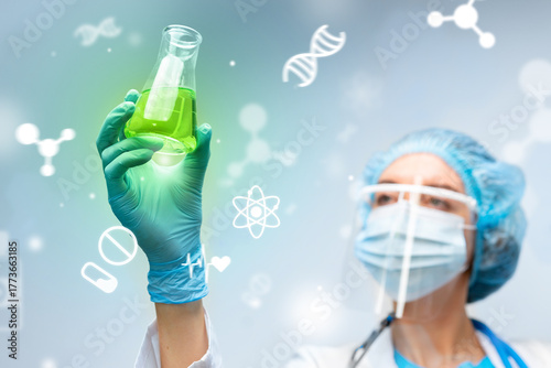 Scientist examines green liquid in flask during laboratory research