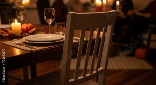 Photo of empty chair at dinner table with candle symbolizing gratitude and remembrance