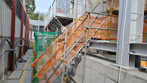 temporary scaffolding stairs with orange safety netting on a building construction site