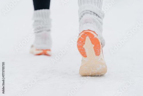 young caucasian woman running in park in winter, sneakers close-up view,, back view, active lifestyle concept, jogging in winter, sports life, copy space