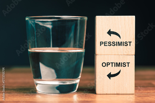 Obraz na plátne Glass of water with wooden blocks labeled optimist and pessimist symbolizing pos