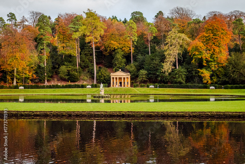 A cropped view of Studley Royal Water Garden in North Yorkshire, with trees and water reflecting warm fall colors under soft seasonal light