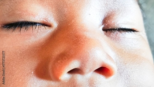 Close-up of a young child's face showing closed eyes and nose in a soft, natural light
