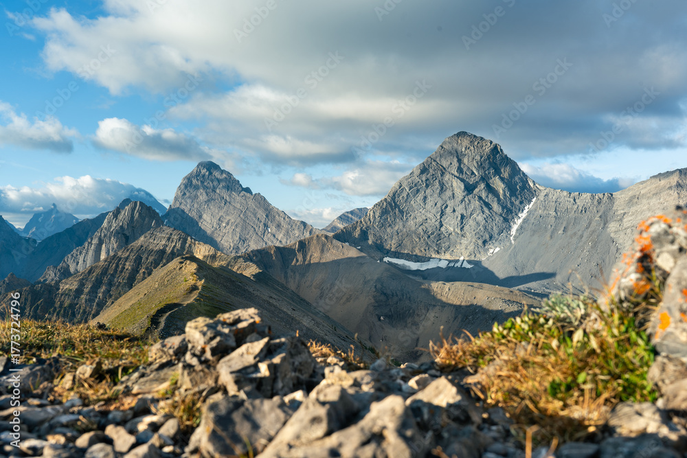 Fototapeta premium Majestic mountain peaks piercing the sky under a partly cloudy afternoon.