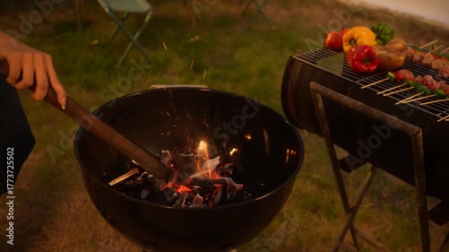 A close-up view of a glowing outdoor fire pit burning wooden sticks at dusk, creating warm light and smoke symbolizing coziness, relaxation, and outdoor gathering atmosphere