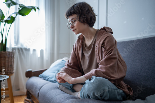 Quadro su tela Anxious upset woman sitting on sofa at home nervously fidgeting with hands