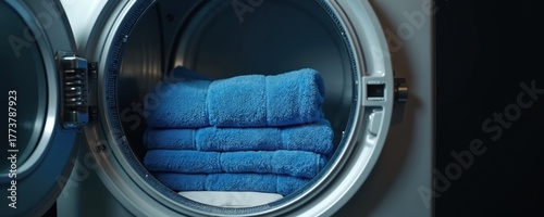 Wallpaper Mural A stack of fluffy blue towels rests inside a clean dryer drum. The appliance door is open revealing the freshly laundered load. Domestic chore completed, soft textiles ready for use. Torontodigital.ca