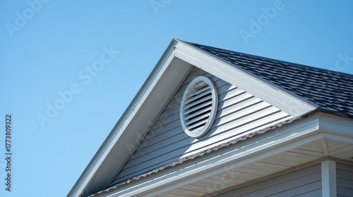 Elegant photo of closeup of a house gable with a louvered vent under a clear blue sky.