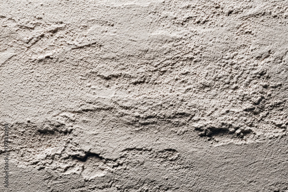 Fototapeta premium Concrete wall with uneven texture and shadows in bright, natural light. Ideal for backgrounds that need a rough, organic, or urban design feel.