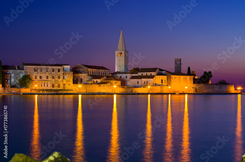 Historic European town glows at twilight, water reflects lights. Rovinj, Croatia
