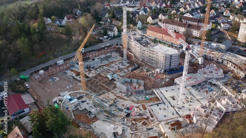 Aerial view of a multi-building residential construction site in Stein, near Nuremberg, Germany. Heavy machinery, cranes, and modular foundations highlight the role of housing and the EU economy.