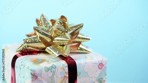 Christmas gift box with golden bow turns on blue background.