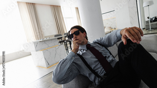 A successful and confident young businessman smokes in his ideal apartment while sitting on the couch
