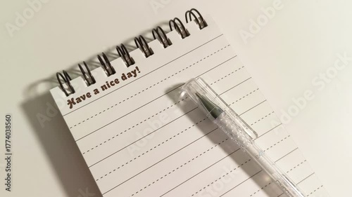 Capture the creative journey of writing in a notebook, with a pen poised to write, encouraging viewers to have a nice day, perfect for inspiration and motivation