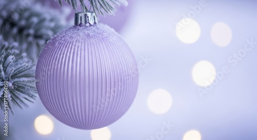 Purple ribbed Christmas ball with glitter hanging on a snowy Christmas tree branch during winter holiday. Festive decoration for Christmas or New Year.