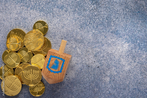 mottled blue background with dreidel and gold chocolate coins for playing the traditional Hanukkah game