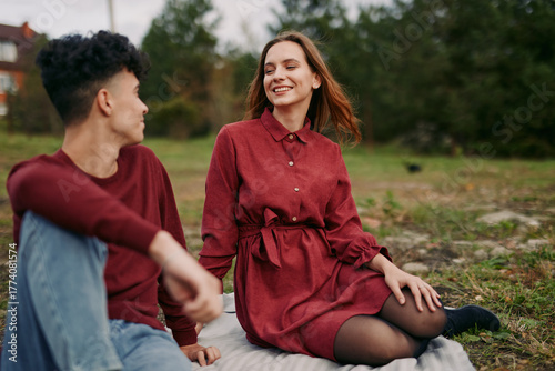 Φωτογραφία Young couple sitting on a blanket in a grassy park, sharing a relaxed candid moment with natural smiles and subtle gestures that capture an authentic, trustworthy everyday connection