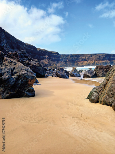 Cliffs on the beach. Extreme landscape of a cliffed coast, white sand beach, and blue sky. Coastal background.