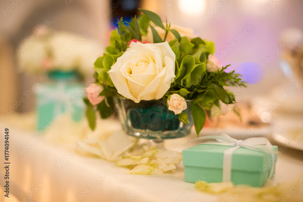 Fototapeta premium Wedding table decoration with roses and gift box. Beautiful wedding table with white roses in vase and turquoise gift boxes as elegant decor
