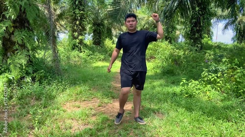 Young man doing leg exercise outdoors in tropical forest area