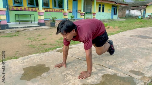 A young Asian man practices plank running at park close-up. Hispanic man exercises