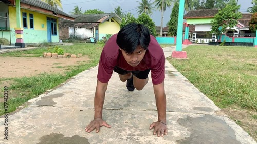 Asian men doing rock climbing exercises while standing plank at the park, slow motion. Athletic men exercising together. Sports concept