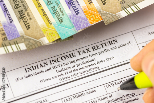  taxes. A man filling out an Indian income tax form, placed on a desk with a calculator and rupees. Selective focus. Financial concept