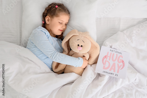 Cute little happy girl in pajamas with toy rabbit and greeting card sleeping ...